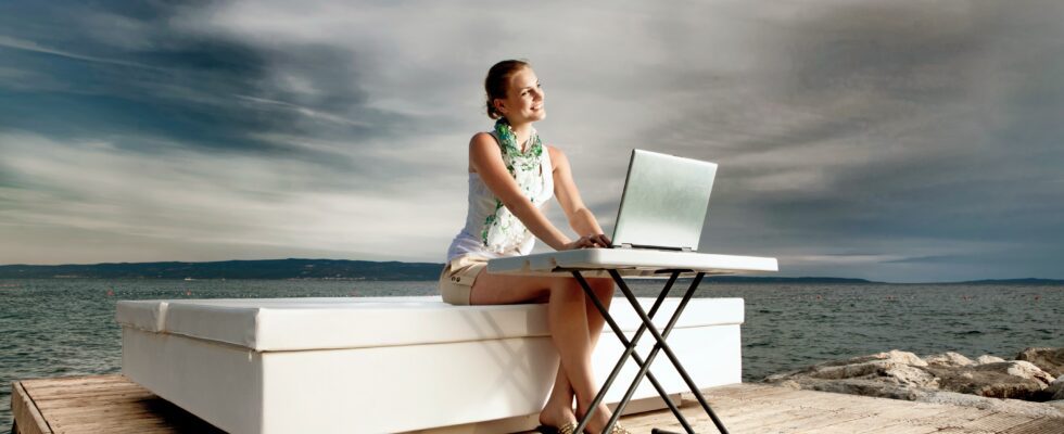 woman in white tank top sitting on white chair using macbook