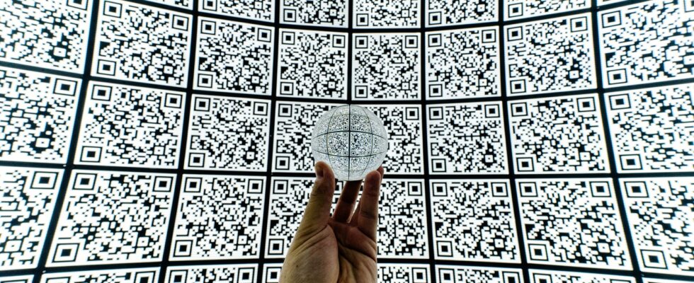 person holding clear glass ball with QR code background