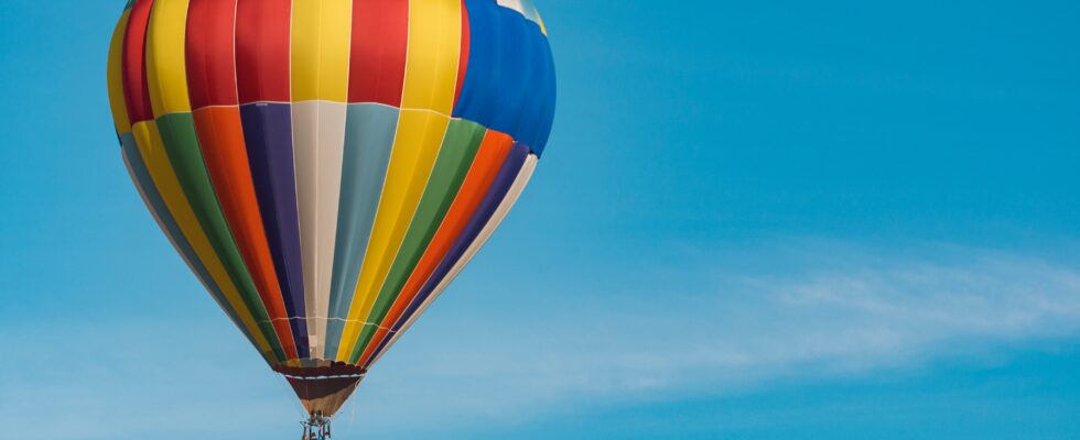 panning photography of flying blue, yellow, and red hot air balloon