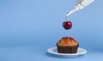 Robot preparing sweet cupcake with cherry, blue background