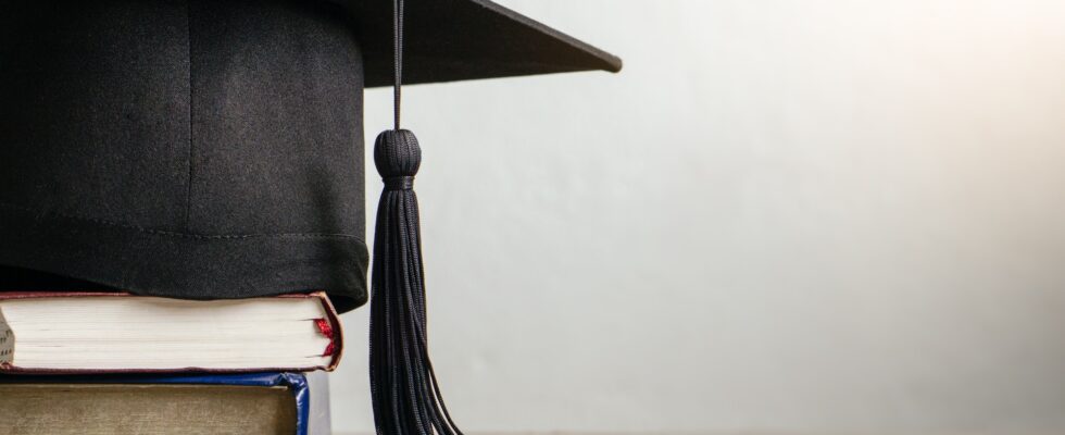 Mortar board with degree paper and books on wood table. graduation concept.