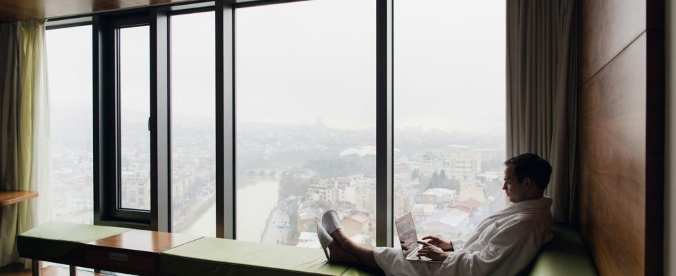 Attractive Man enjoying his morning coffee on his computer at his hotel room