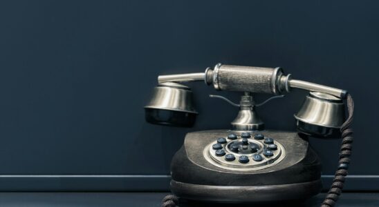 black and brown rotary phone near gray wall