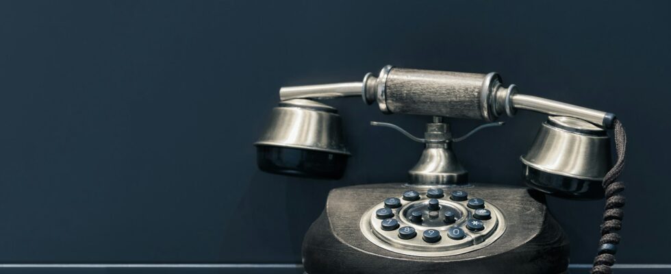 black and brown rotary phone near gray wall