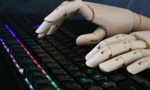 AI artificial intelligence concept - robot hands typing on lit keyboard