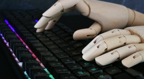 AI artificial intelligence concept - robot hands typing on lit keyboard