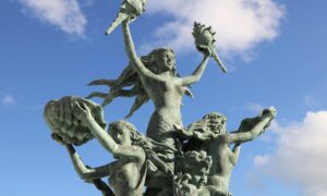 Sculpture of mermaids on a blue cloudy sky background