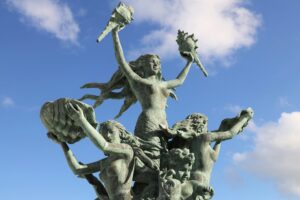 Sculpture of mermaids on a blue cloudy sky background