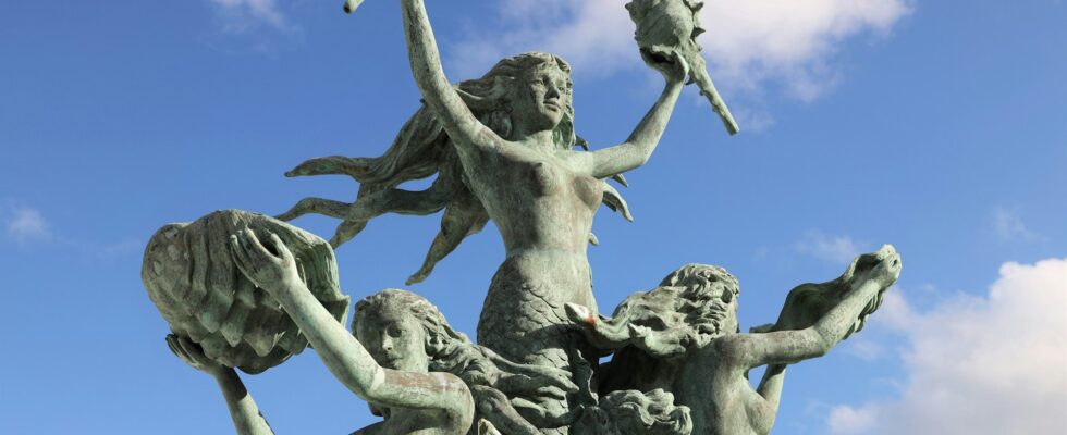 Sculpture of mermaids on a blue cloudy sky background