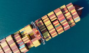 Aerial top view of cargo ship carrying container and running for export goods from cargo yard