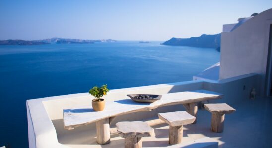 bench and dining table near body of water under calm sky