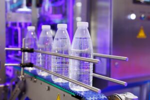 The PET bottles in the rail on the conveyor belt for filling process in the drinking water factory.