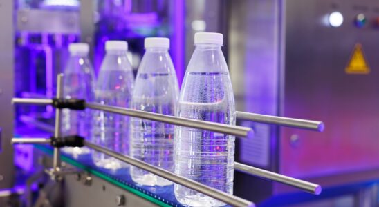 The PET bottles in the rail on the conveyor belt for filling process in the drinking water factory.